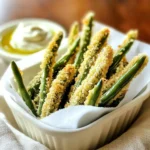 - 450 g frische grüne Bohnen - 125 g Weizenmehl - 2 große Eier Die Hauptzutaten sind einfach und leicht zu finden. Frische grüne Bohnen sorgen für einen knackigen Biss. Das Weizenmehl hilft, die Bohnen gut zu panieren. Die Eier binden die Panade und geben einen tollen Geschmack. - Knoblauchpulver, Zwiebelpulver, Cayennepfeffer - 250 g Semmelbrösel (Panko empfohlen) - 50 g geriebener Parmesan Die Gewürze bringen viel Geschmack. Knoblauchpulver gibt eine würzige Note. Zwiebelpulver ergänzt den Geschmack. Cayennepfeffer fügt eine leichte Schärfe hinzu, wenn du magst. Panko-Semmelbrösel sind perfekt für extra Knusprigkeit. Parmesan macht die Pommes noch leckerer. - 2 Esslöffel Olivenöl - Salz und Pfeffer Olivenöl sorgt für einen schönen Crunch und Geschmack. Salz und Pfeffer runden die Aromen ab. Diese Zutaten machen das Rezept einfach und köstlich. Heize deinen Ofen auf 220°C vor. Dies sorgt für eine perfekte Knusprigkeit. Lege ein Backblech mit Backpapier aus. Das macht die Reinigung einfacher. Mische das Weizenmehl mit dem Knoblauchpulver, Zwiebelpulver und Cayennepfeffer in einer Schüssel. Vergiss nicht, auch Salz und Pfeffer hinzuzufügen. Rühre gut um, damit alles gleichmäßig verteilt ist. In einer anderen Schüssel schlägst du die Eier auf. Rühre sie gut, bis sie schaumig sind. Nimm die frischen grünen Bohnen und tauche jede Bohne zuerst in die Mehlmischung. Schüttele das überschüssige Mehl ab. Tauche die bemehlte Bohne dann in das verquirlte Ei. Lass das überschüssige Ei abtropfen. Rolle die Bohne in der Semmelbrösel- und Parmesan-Mischung, bis sie vollständig bedeckt ist. Lege die panierten Bohnen auf das Backblech. Achte darauf, dass sie sich nicht berühren. Beträufle die grünen Bohnen mit Olivenöl. Dies gibt ihnen mehr Geschmack und einen tollen Crunch. Backe die Bohnen 15-20 Minuten, bis sie goldbraun sind. Wende sie einmal während des Backens, damit sie gleichmäßig garen. Nach dem Backen lasse sie kurz abkühlen, bevor du sie servierst. Um die perfekte Knusprigkeit zu erreichen, empfehle ich die Verwendung von Panko-Semmelbröseln. Sie sind grober und sorgen für einen tollen Crunch. Stelle sicher, dass du die Bohnen nicht überfüllst. Wenn sie zu eng auf dem Blech liegen, können sie dampfen und verlieren ihre Knusprigkeit. Du kannst die Gewürze nach deinem Geschmack anpassen. Füge Kräuter wie Oregano oder Paprika hinzu. Wenn du eine vegane Version machen möchtest, ersetze die Eier durch eine Mischung aus Wasser und Leinsamen. Das gibt der Panade eine gute Bindung. Ich liebe es, diese Pommes mit Dips zu servieren. Marinara-Sauce oder Knoblauch-Aioli passen perfekt dazu. Für die Präsentation kannst du die Bohnen in einem kleinen Korb oder einem Pappbecher anrichten. Das sieht nicht nur gut aus, sondern macht auch Spaß beim Essen. {{image_4}} Du kannst die grünen Bohnen leicht durch andere Gemüse ersetzen. Zucchini-Pommes sind eine tolle Wahl. Sie werden knackig und schmecken hervorragend. Karotten-Pommes sind eine weitere gute Option. Sie geben einen süßeren Geschmack und eine schöne Farbe. Wenn du glutenfrei kochen möchtest, gibt es einfache Lösungen. Verwende glutenfreies Mehl anstelle von Weizenmehl. Auch glutenfreie Semmelbrösel sind eine gute Wahl. Sie sorgen für die gleiche schöne Knusprigkeit. Möchtest du es schärfer? Das ist einfach! Füge mehr Cayennepfeffer oder Chili-Pulver hinzu. Diese Gewürze geben den Pommes einen aufregenden Kick. Probiere es aus, um die perfekte Schärfe für deinen Geschmack zu finden. Um deine Knoblauch Parmesan grünen Bohnen Pommes frisch zu halten, lege sie in einen luftdichten Behälter. Achte darauf, dass sie vollständig abgekühlt sind, bevor du sie lagerst. So vermeidest du, dass sie matschig werden. Im Kühlschrank bleiben sie bis zu drei Tage frisch. Wenn du sie länger aufbewahren möchtest, ist das Einfrieren eine gute Option. Um die Pommes einzufrieren, folge diesen einfachen Schritten: 1. Lass die Pommes vollständig abkühlen. 2. Lege sie in einer einzigen Schicht auf ein Backblech. 3. Friere die Pommes für etwa eine Stunde ein, bis sie fest sind. 4. Übertrage die gefrorenen Pommes in einen luftdichten Gefrierbeutel. 5. Vergiss nicht, das Datum auf den Beutel zu schreiben. So weißt du, wie lange sie schon eingefroren sind. Die Pommes können bis zu drei Monate im Gefrierschrank bleiben. Wenn es Zeit ist, die Pommes wieder zu genießen, gibt es einige beste Methoden zum Aufwärmen: - Ofen: Heize deinen Ofen auf 200°C vor. Lege die Pommes auf ein Backblech und backe sie für 10-15 Minuten. So werden sie wieder knusprig. - Mikrowelle: Wenn du es eilig hast, kannst du die Pommes auch in der Mikrowelle aufwärmen. Achte darauf, sie nicht zu lange zu erhitzen, da sie weich werden können. - Luftfritteuse: Diese Methode gibt dir die beste Knusprigkeit zurück. Heize die Luftfritteuse auf 180°C vor und erhitze die Pommes für 5-7 Minuten. Egal, wie du sie aufwärmst, genieße den köstlichen Geschmack! Frische grüne Bohnen sind bei guter Lagerung etwa 5 bis 7 Tage haltbar. Lagere sie im Kühlschrank in einem luftdichten Behälter. So bleiben sie knackig und frisch. Achte darauf, dass die Bohnen fest und grün sind. Wenn sie weich oder fleckig werden, solltest du sie wegwerfen. Ja, du kannst die Bohnen im Voraus vorbereiten. Panier die Bohnen und lege sie auf ein Backblech. Decke das Blech mit Frischhaltefolie ab und stelle es in den Kühlschrank. So kannst du die Bohnen bis zu 24 Stunden im Voraus vorbereiten. Backe sie einfach, wenn du bereit bist. Das spart Zeit und macht das Snacken einfacher. Ja, diese Pommes sind eine gesunde Snack-Option. Grüne Bohnen sind reich an Vitaminen und Ballaststoffen. Der Parmesan gibt Geschmack, aber in Maßen. Verwende Panko für einen knusprigen Biss und weniger Öl, um die Kalorien niedrig zu halten. So kannst du diesen Snack ohne schlechtes Gewissen genießen. Grüne Bohnen-Pommes sind einfach zuzubereiten. Wir haben frische Bohnen, Mehl, Eier und eine leckere Panade verwendet. Die Zubereitungsschritte waren leicht und führten zu knusprigen Bohnen. Tipps für Variationen und Lagerung erweitern die Möglichkeiten. Denke daran, deine Bohnen nach den besten Tipps zu lagern und aufzuwärmen. Mit diesen leckeren Pommes bist du bereit, deine Familie oder Freunde zu beeindrucken. Lass deiner Kreativität freien Lauf und genieße dein Gericht. Viel Spaß beim Ausprobieren!